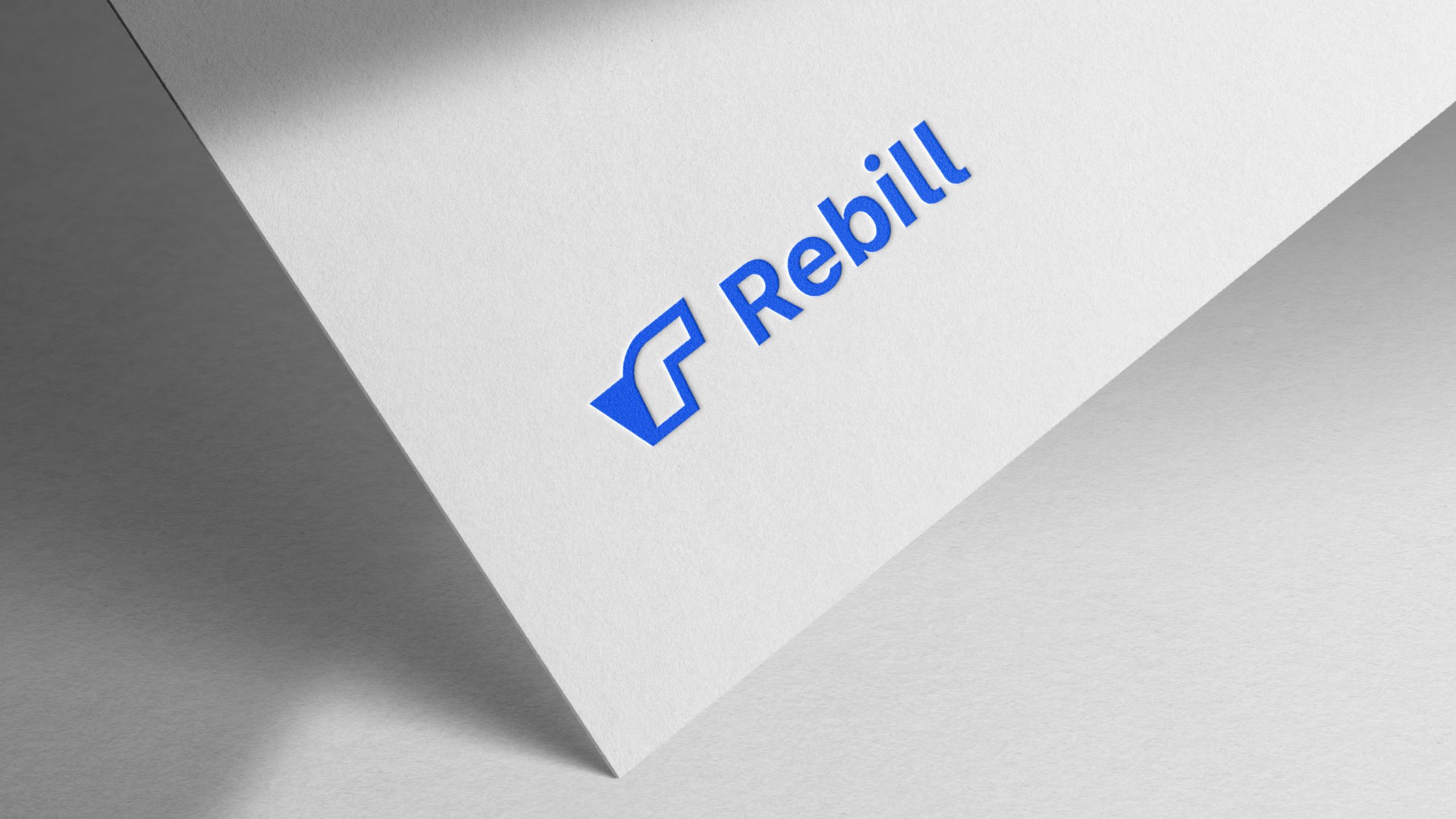 Rebill logo in bright blue on an angled white card, part of the new visual identity Kundo Studio designed to position Rebill as a Stripe-grade payments infrastructure platform for LATAM.