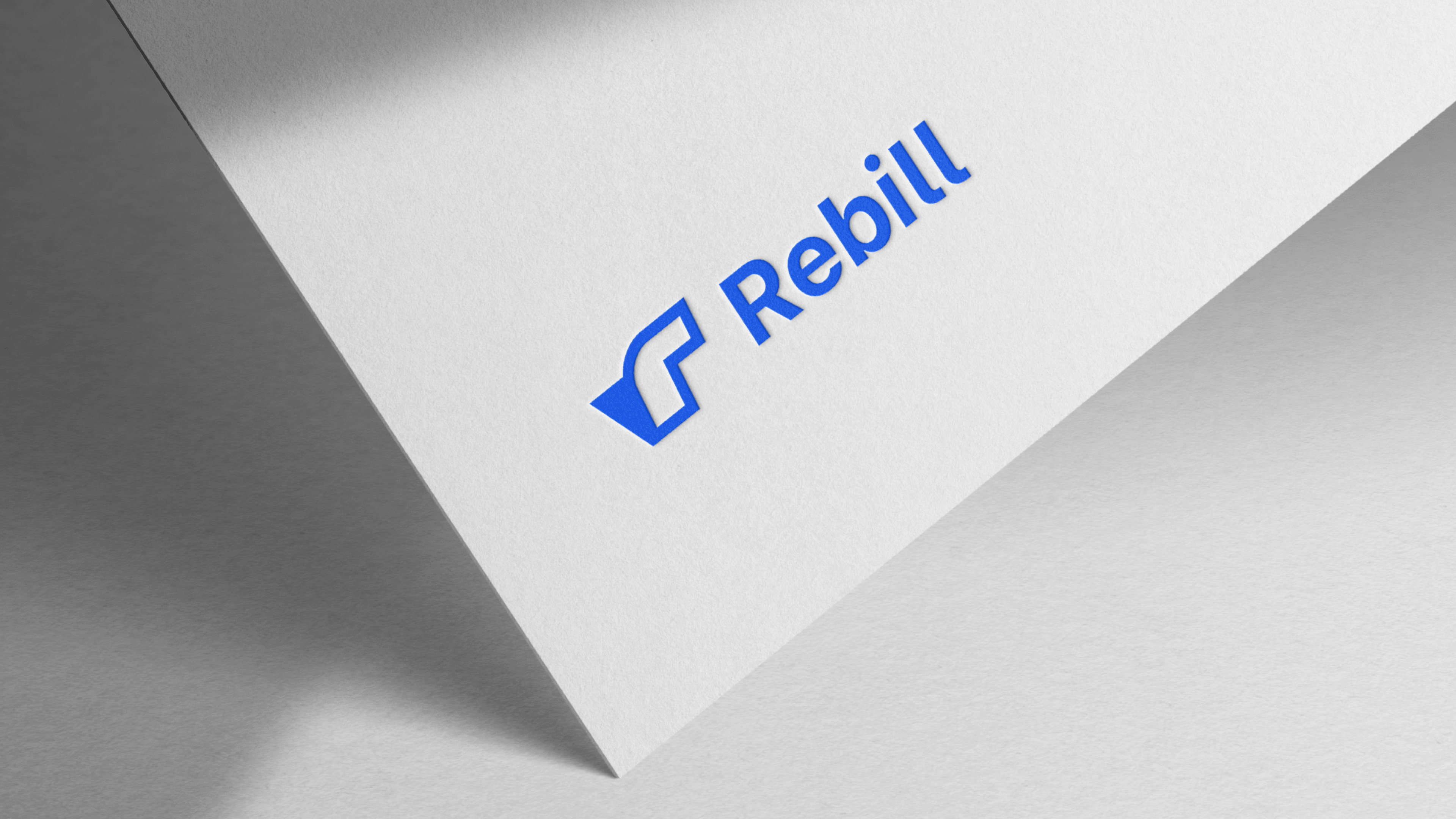 Rebill logo in bright blue on an angled white card, part of the new visual identity Kundo Studio designed to position Rebill as a Stripe-grade payments infrastructure platform for LATAM.